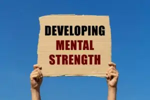 A person holding up a sign that says "developing mental strength" while embracing the concept of lifelong learning.