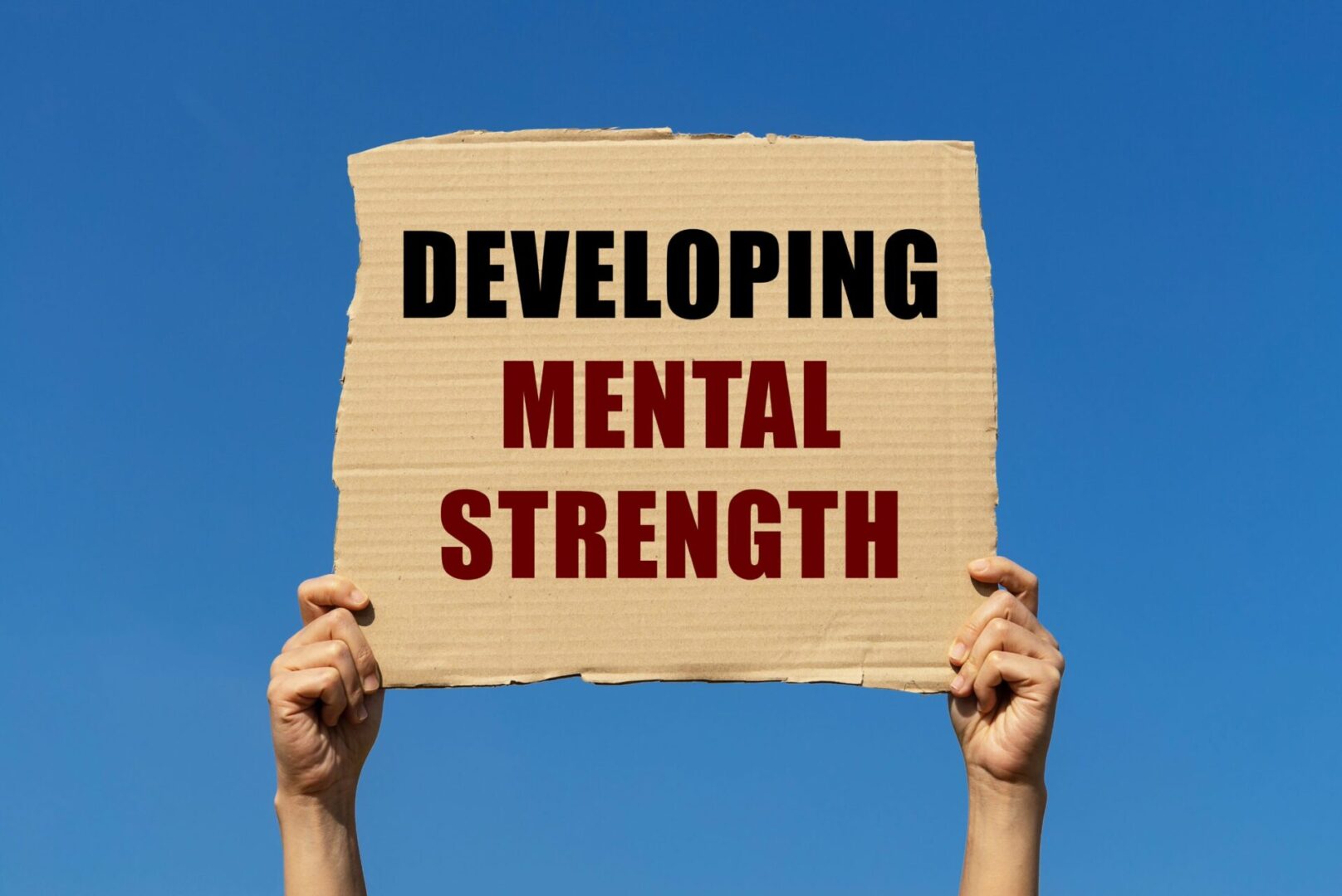 A person holding up a sign that says "developing mental strength" while embracing the concept of lifelong learning.